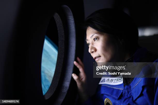 a commercial space traveler looking at the earth through window of the spaceship. - space tourism stockfoto's en -beelden