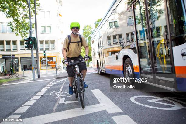 ciclista masculino andando em uma ciclovia no centro da cidade. algum tráfego irreconhecível em segundo plano. - single lane road - fotografias e filmes do acervo