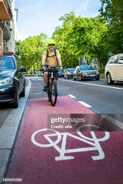 radfahrer, der auf einem radweg im stadtzentrum fährt. etwas unkenntlicher verkehr im hintergrund. - bicycle lane stock-fotos und bilder