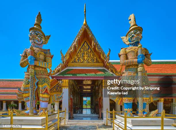 two big guardians statues standing guard at the gate inside  of wat phra kaew, bangkok. - fine art statue stock pictures, royalty-free photos & images