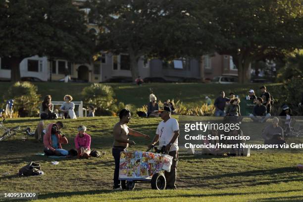 Alberto Sanchez, right, is offered a dollar for a popsicle in Dolores Park in the Mission District of San Francisco, Calif., on Wednesday, October 8,...