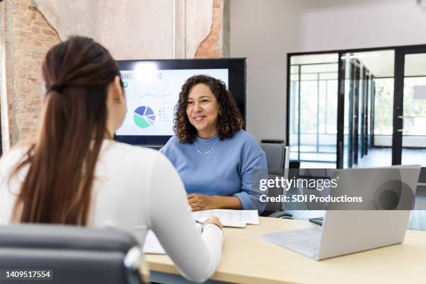 female co-workers meet to discuss marketing initiatives - employee review imagens e fotografias de stock