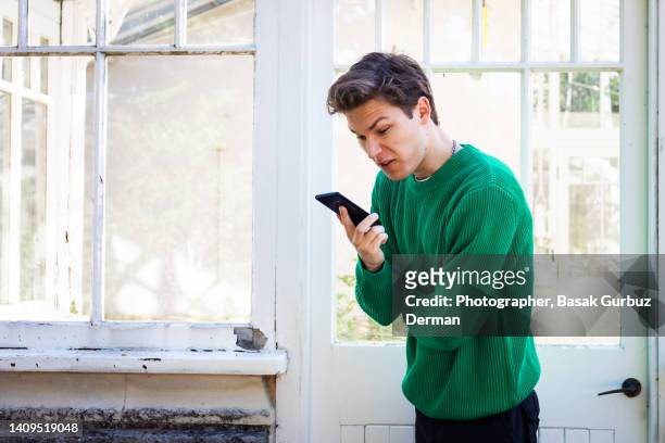 angry young man shouting on mobile phone - hate palabra en inglés fotografías e imágenes de stock