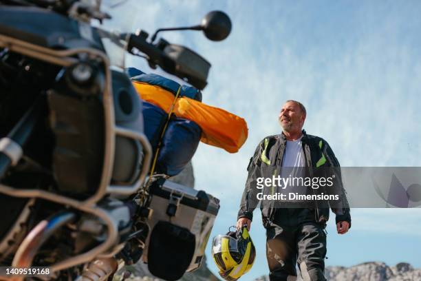 smiling motorcycle rider and bike outdoors - motorcycle rider stock pictures, royalty-free photos & images