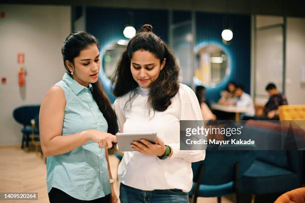 two women standing and discussing in the co-working office - india discussion imagens e fotografias de stock