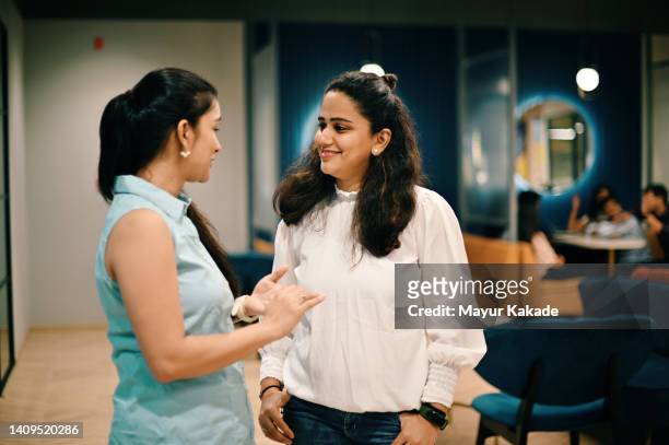 two women standing and discussing in the co-working office - happy asian woman bright office stock-fotos und bilder