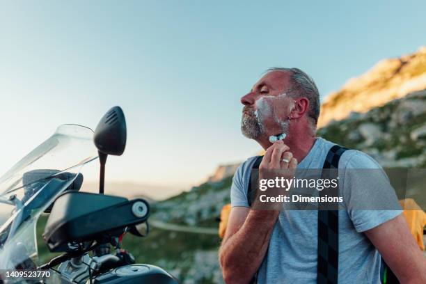 motociclista che si rade con il rasoio sullo specchio della moto - toiletries foto e immagini stock