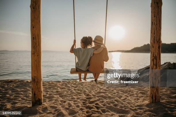 brother and sister swinging by the sea - macedonia greece stock pictures, royalty-free photos & images