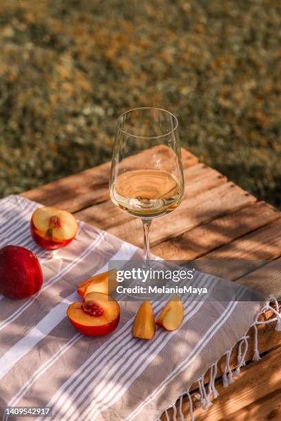 white wine glass in summer garden with peaches on wooden crate picnic - wine picnic stock pictures, royalty-free photos & images