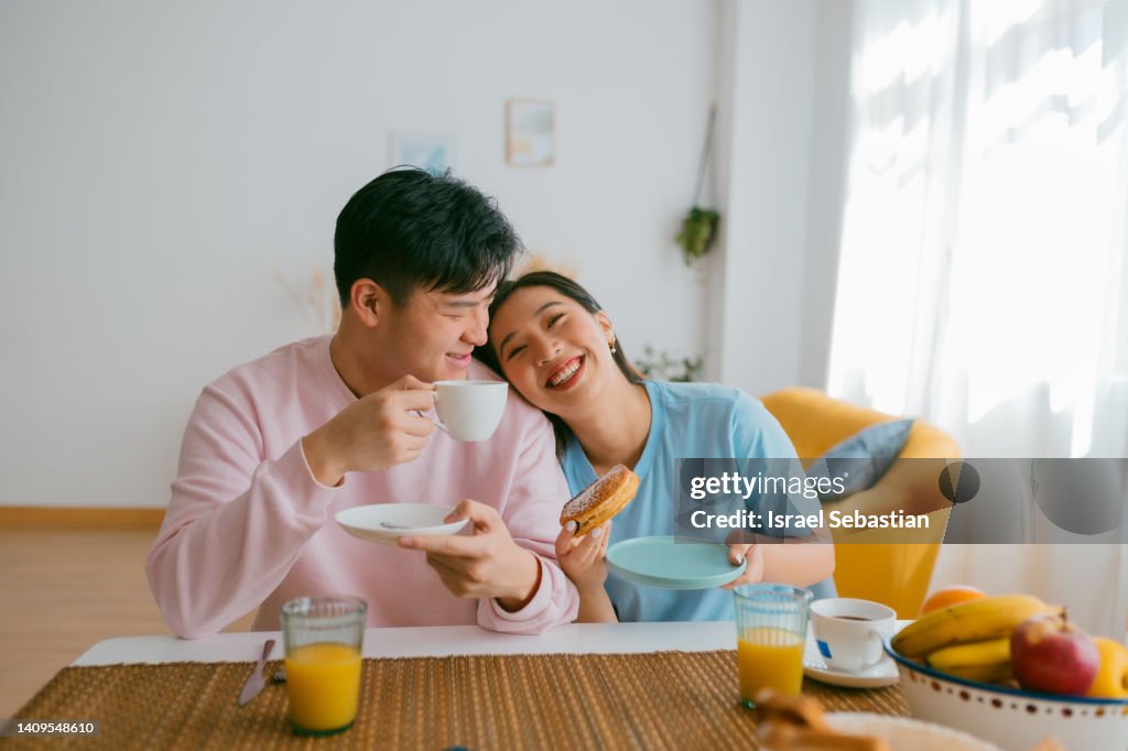 Loving Asian couple having breakfast together at home.
