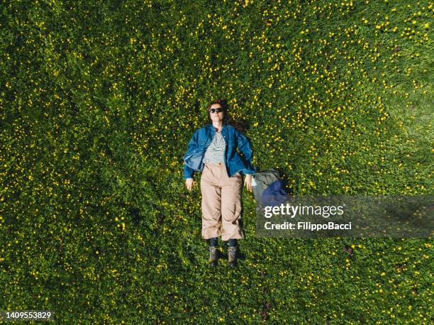 une femme est allongée sur l’herbe entourée de fleurs jaunes - pré vu du ciel photos et images de collection