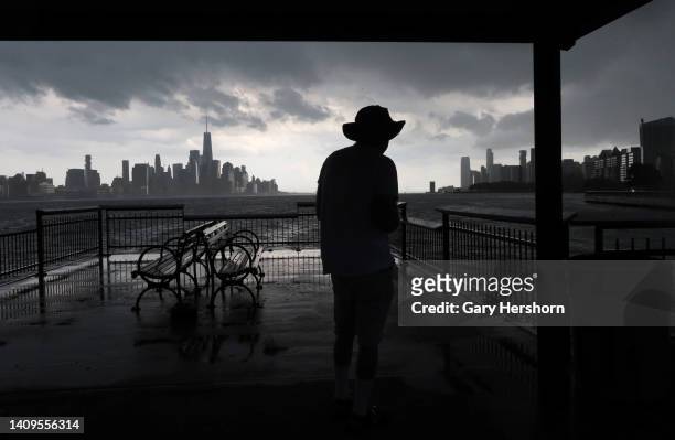 Person watches a thunderstorm move across the Hudson River towards lower Manhattan and One World Trade Center in New York City on July 18 as seen...