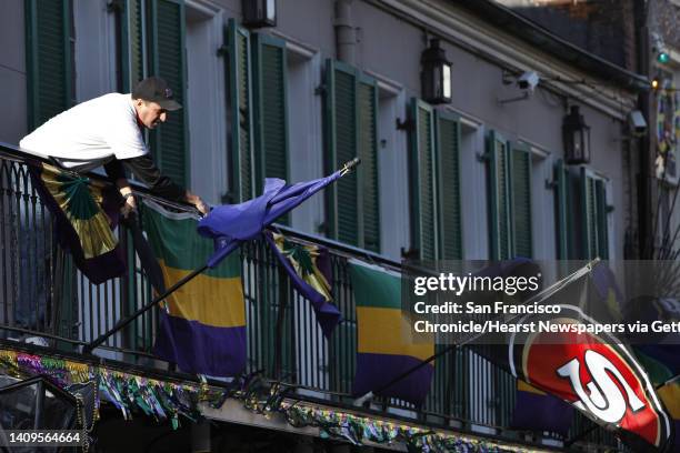 Andy Steib, the DJ at the Cat's Meow, fixes some Super Bowl team banners hanging from the balcony of the club on Bourbon Street on Wednesday, January...