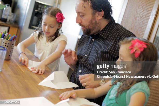 Joshua Safran shows his daughters Ketriel left, and Sivan how to make paper airplanes at their Oakland, Calif., home on Sunday, August 18, 2013....