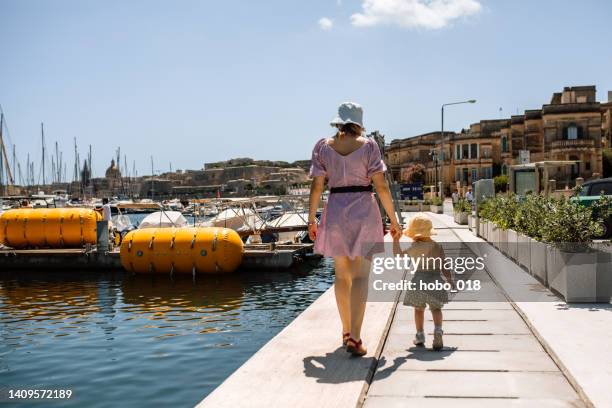 mother and her little daughter walking by the sea - malta harbour stock pictures, royalty-free photos & images