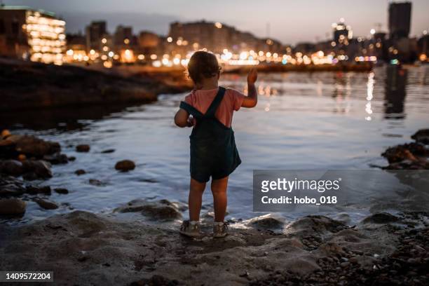 little girl throwing little rocks in the water - malta harbour stock pictures, royalty-free photos & images