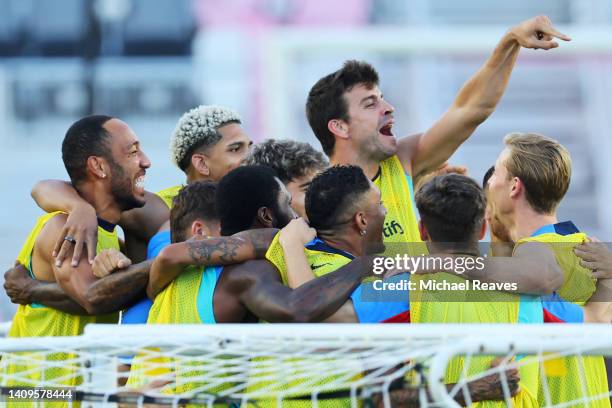 Pierre-Emerick Aubameyang and Gerard Pique of FC Barcelona react in a huddle during a training session ahead of the preseason friendly against Inter...
