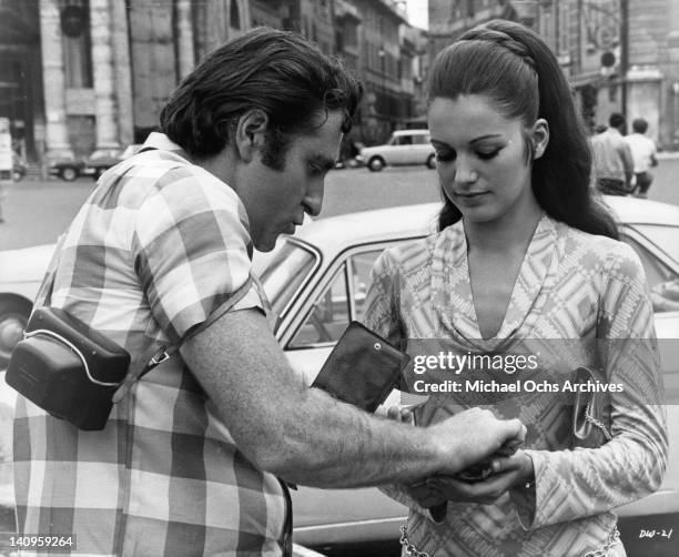 Marty Ingels handing money to unidentified woman in a scene from the film 'If It's Tuesday, This Must Be Belgium', 1969.