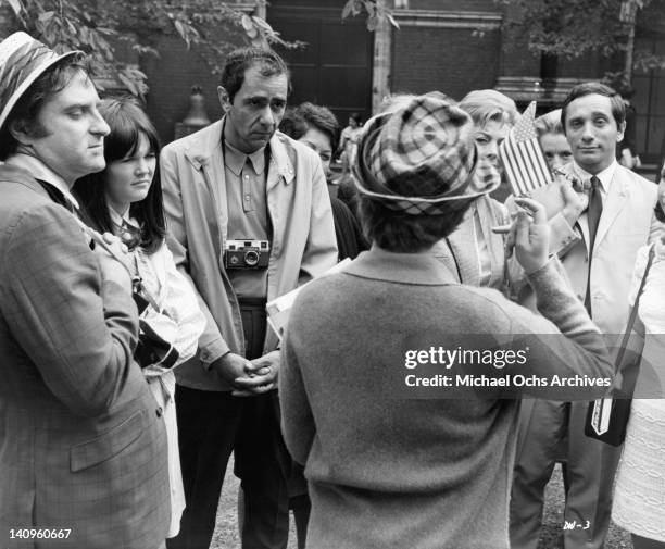 Marty Ingels, Hilary Thompson, Michael Constantine, and Sandy Baron listening to woman holding little American flag a scene from the film 'If It's...