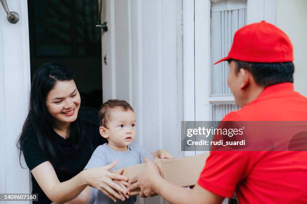 woman receiving package delivery with her infant son - family front door imagens e fotografias de stock