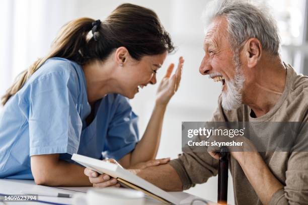陽気な在宅介護者と家で笑う先輩男性。 - 老年医学 ストックフォトと画像