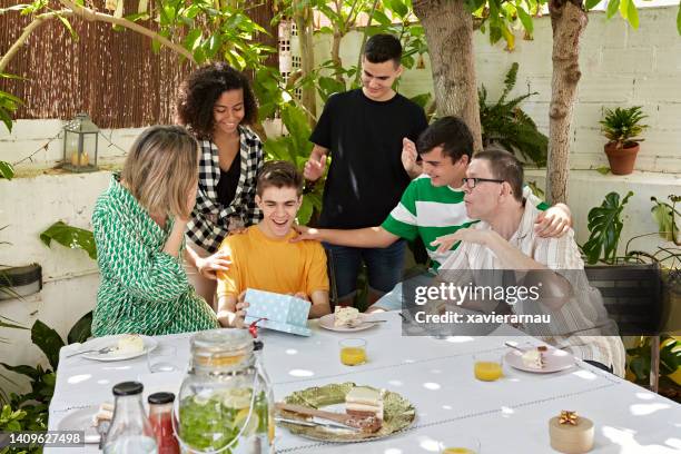 happy teenage boy eröffnungsgeschenk auf einer outdoor-party - boy gift stock-fotos und bilder