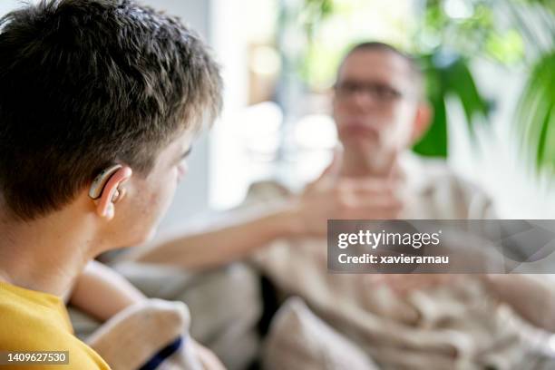 deaf teenager signing with his father in family home - hearing aids stock pictures, royalty-free photos & images