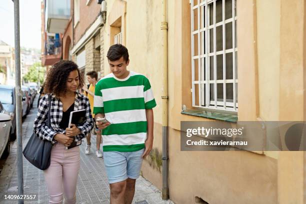 teenage friends coming back from school checking mobile phone - girls of spain stock pictures, royalty-free photos & images