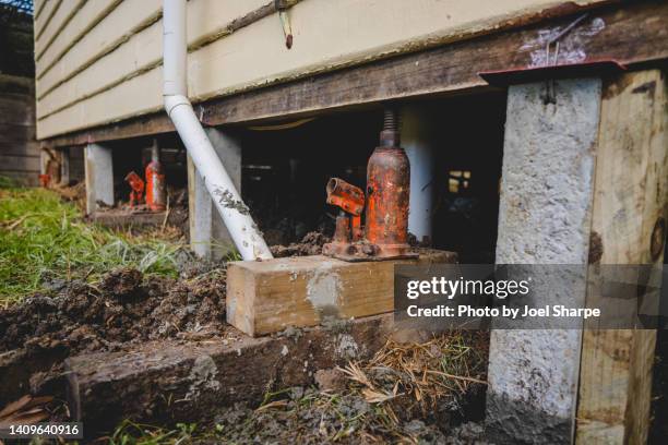 a series of jacks under a clapboard house during the re-stumping process - building foundations stock pictures, royalty-free photos & images