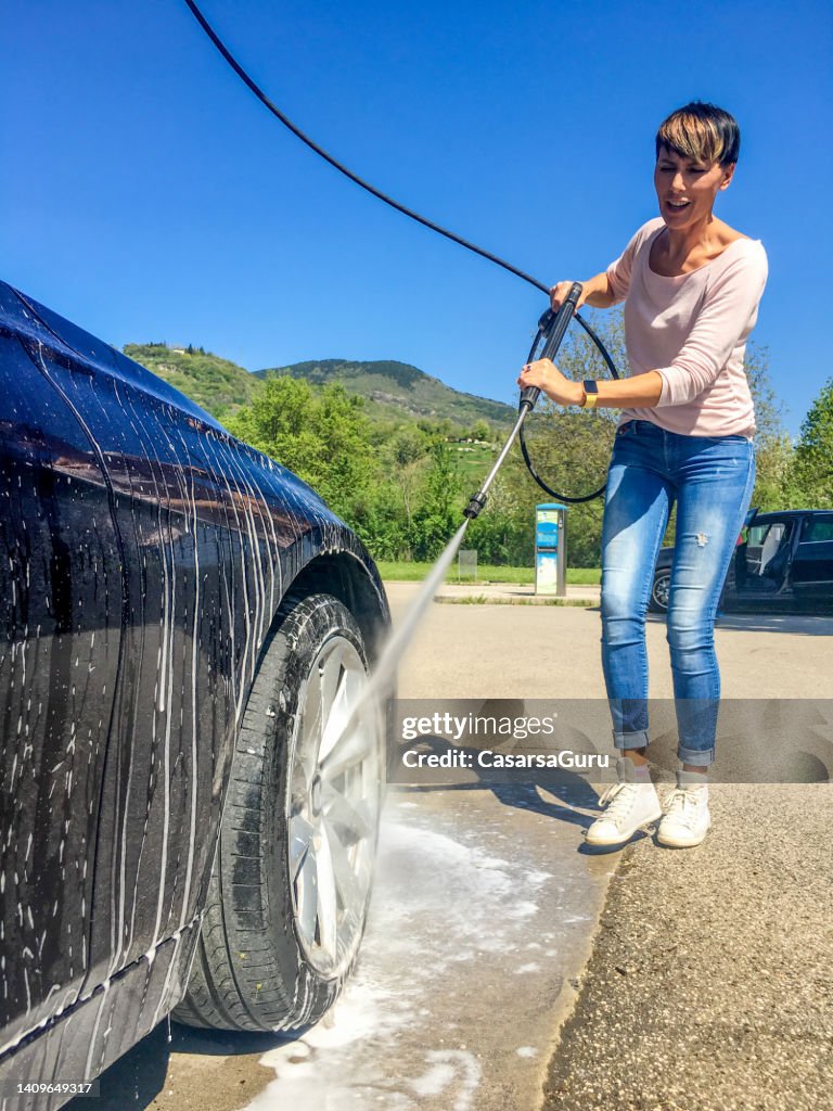 Smiling Adult Woman Cleaning Her Car in Car Wash