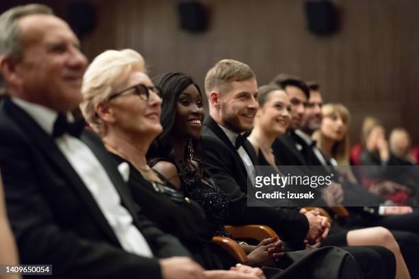 smiling spectators sitting in the theater - british film reception inside stock pictures, royalty-free photos & images