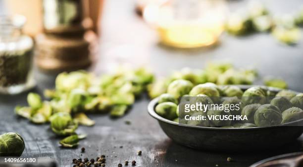 close up of raw brussel sprouts in bowl on kitchen table at blurred background. - brussels sprout stock-fotos und bilder