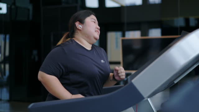 Fat woman trying her best to run on a treadmill.