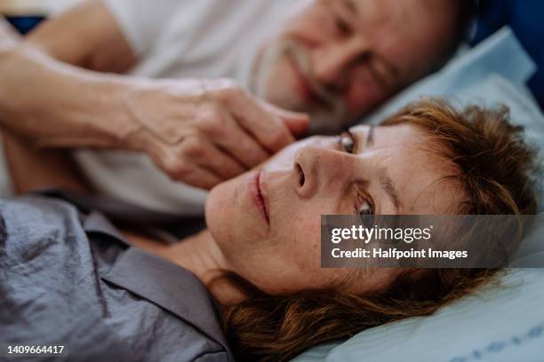 man stroking his sad wife, lying in bed. - cheating wife stockfoto's en -beelden