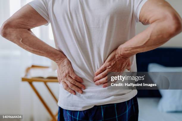 senior man having back pain, standing in his bedroom. - back pain bed stock pictures, royalty-free photos & images
