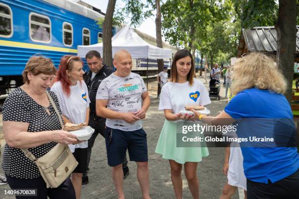 People hold free dishes during a cooking master class for residents of “Iron Town” on July 10, 2022 in Irpin, Ukraine. During the open-air master...