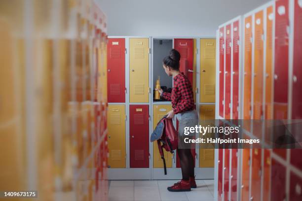 side view of teenage girl in locker room. - red lockers stock pictures, royalty-free photos & images