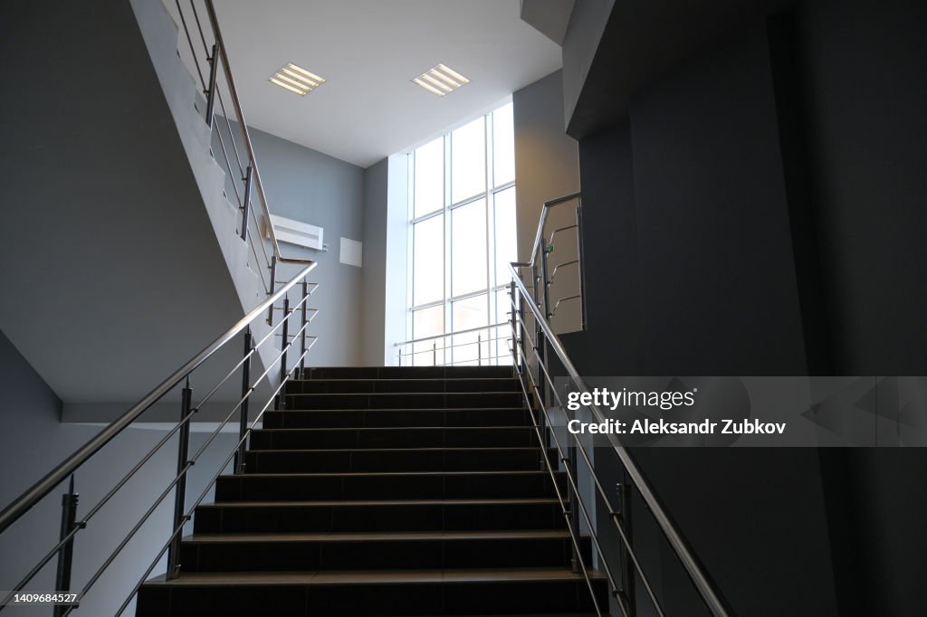 An Empty Staircase In A College, School, Office Building Or Shopping Mall. Emergency exit of a public building. There are no people. Closed premises due to a pandemic, quarantine, virus. Stay at home.