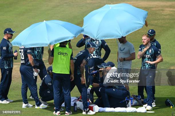 England players take shelter from the hot weather under umbrella's during the drinks break during the First Royal London ODI match between England...