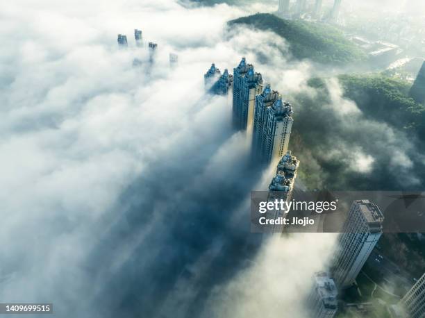 skyscraper emerging through clouds - smog stock-fotos und bilder
