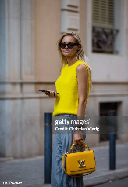 Claire Rose Cliteur is seen wearing yellow sleeveless knit, grey pants, Louis Vuitton bag, sunglasses, heels during a Summer Street Style shoot on...