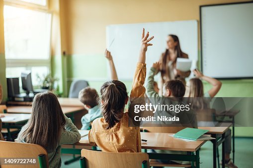Alunos levantando as mãos enquanto professor faz perguntas em sala de aula Alunos levantando as mãos enquanto professor faz perguntas em sala de aula