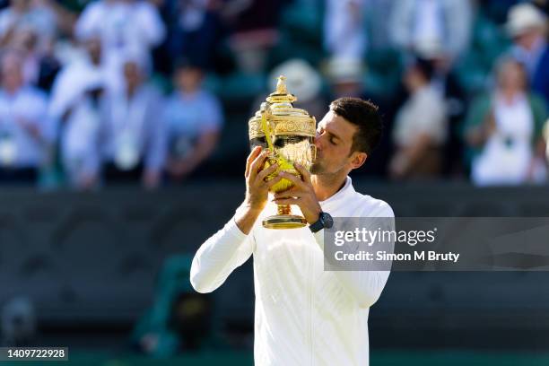 Novak Djokovic of Serbia kisses the trophy after victory in the Mens Singles Final against Nick Kyrgios of Australia at The Wimbledon Lawn Tennis...