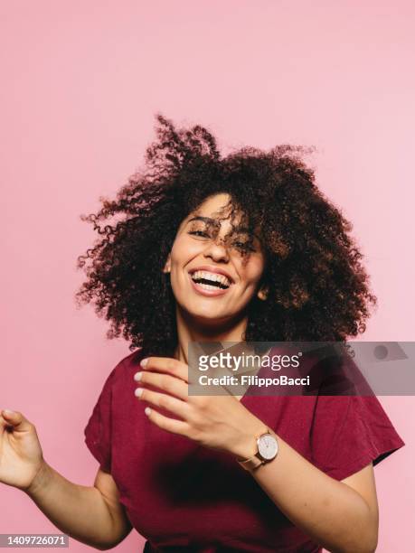 young adult woman is dancing against a pink background - afro stock pictures, royalty-free photos & images