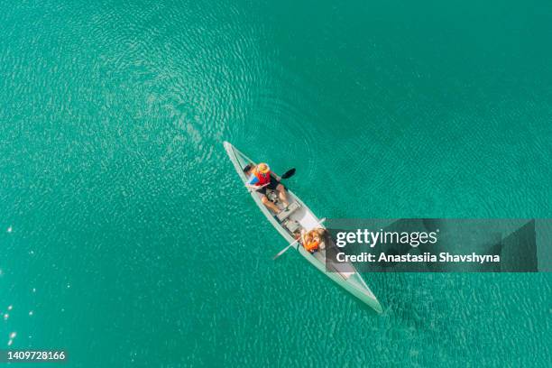 aerial view of a woman and man sailing in a canoe with a dog on crystal blue lake in norway - two people canoeing on a lake stock pictures, royalty-free photos & images