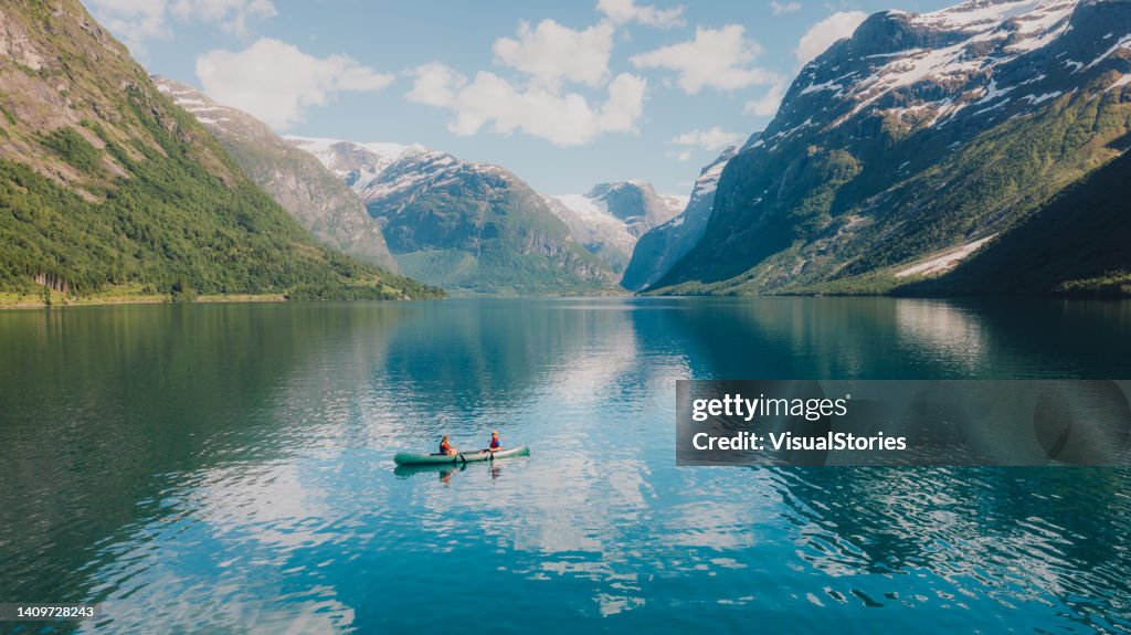ノルウェーの夏をロヴァトネット湖でカヌーで過ごす女性と男性の航空写真