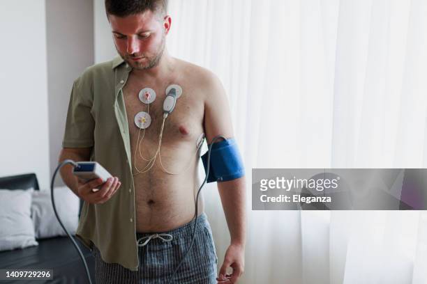 young man  with cardio monitor. study of the work of the heart, cardiology. holter monitor. medical diagnostics. health care, hospital. ecg sensors - electrocardiogram and blood pressure measurement - holter monitor 個照片及圖片檔
