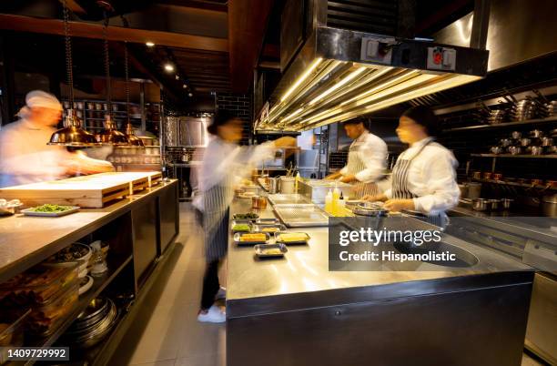 hectic cooks working in a busy commercial kitchen at a restaurant - commerciële keuken stockfoto's en -beelden