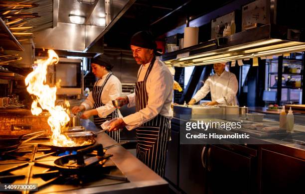 chef cocinando en un restaurante y quemando la comida - uniforme de chef fotografías e imágenes de stock