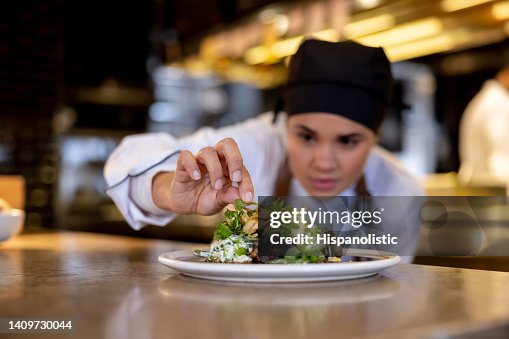 Chef decorating a plate while working at a commercial kitchen Chef decorating a plate while working at a commercial kitchen